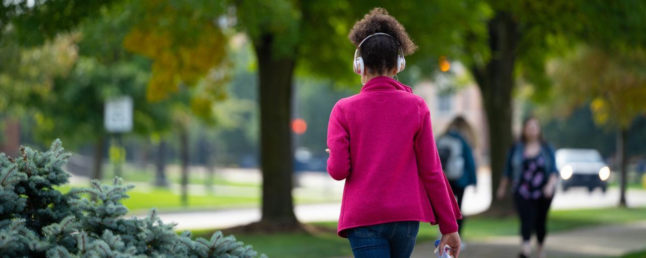 student walking outside with headphones on